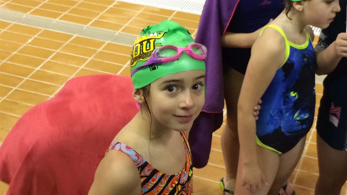 Zoë as a child with a green club cap and goggles on her forehead