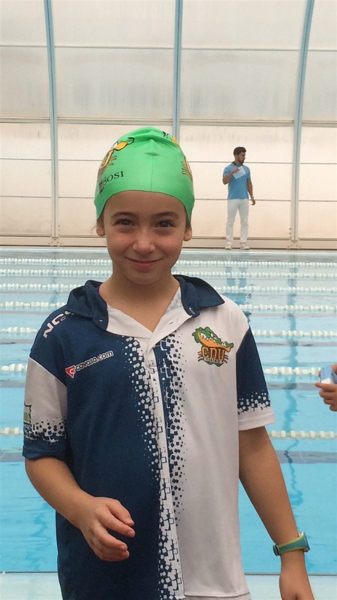 Zoë as a child in a green cap and club polo shirt by the pool