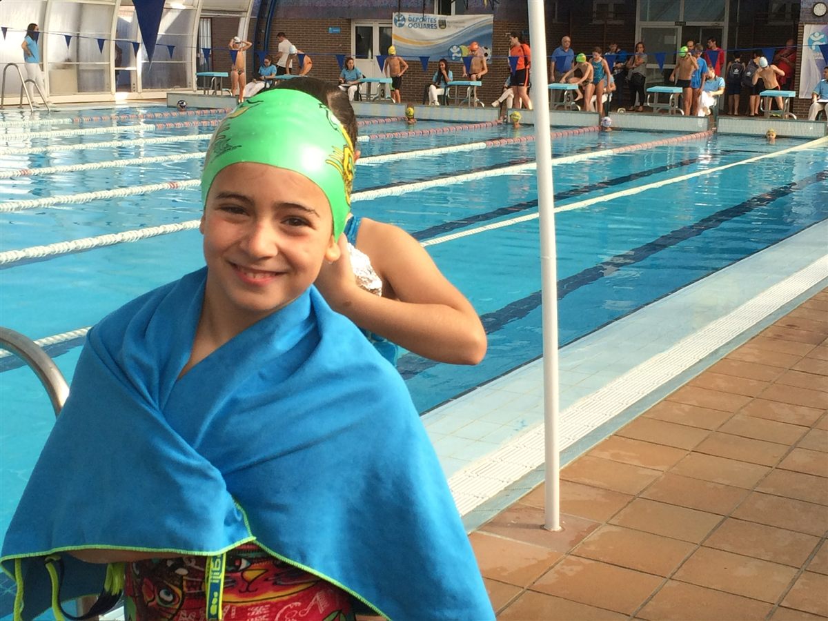 Zoë smiling, wrapped in a blue towel beside the pool