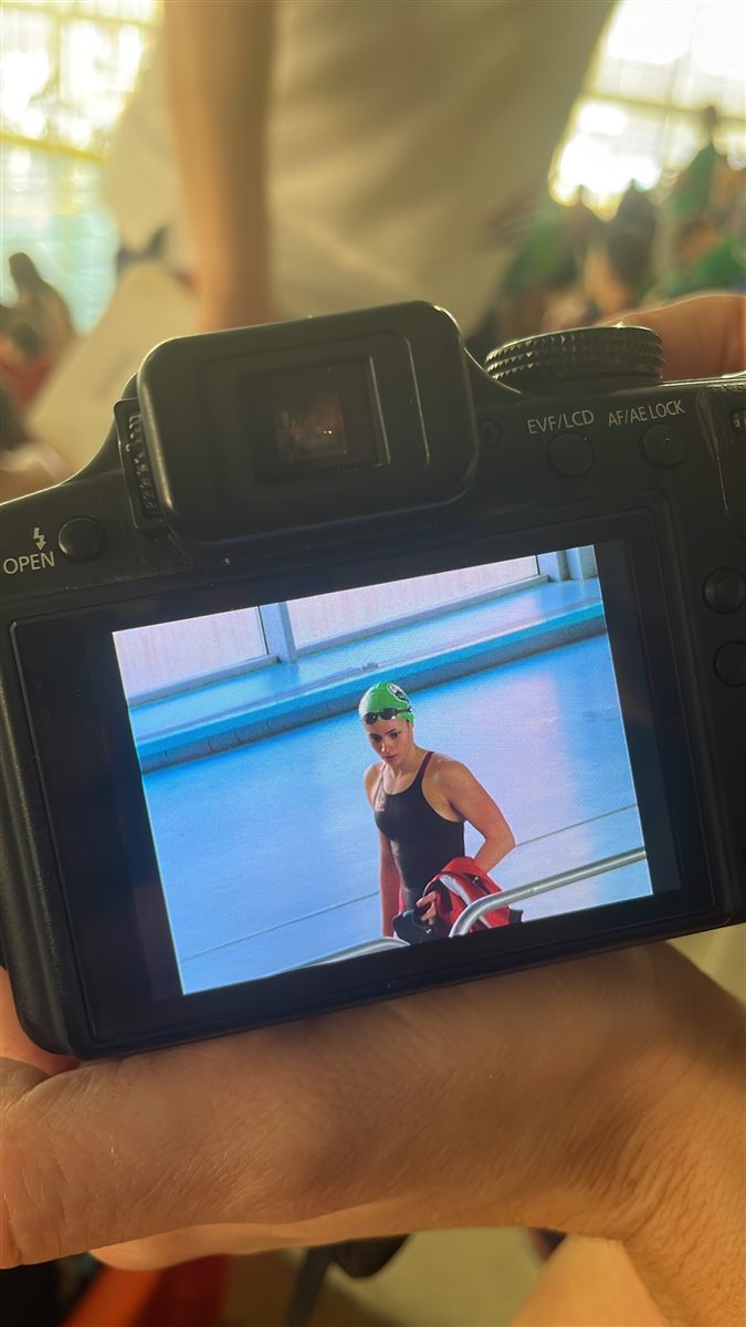 A camera screen showing Zoë in a green cap by the pool