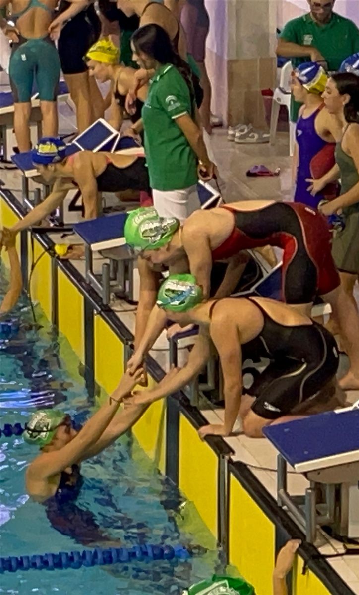 Relay changeover: one swimmer touches the wall as the next dives in
