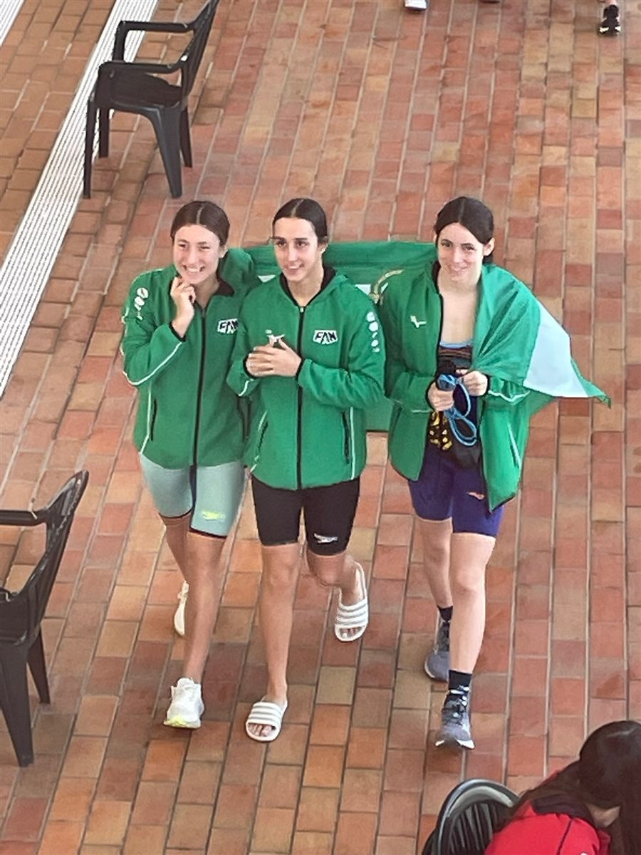 Three swimmers in the green tracksuit of the Andalusian team