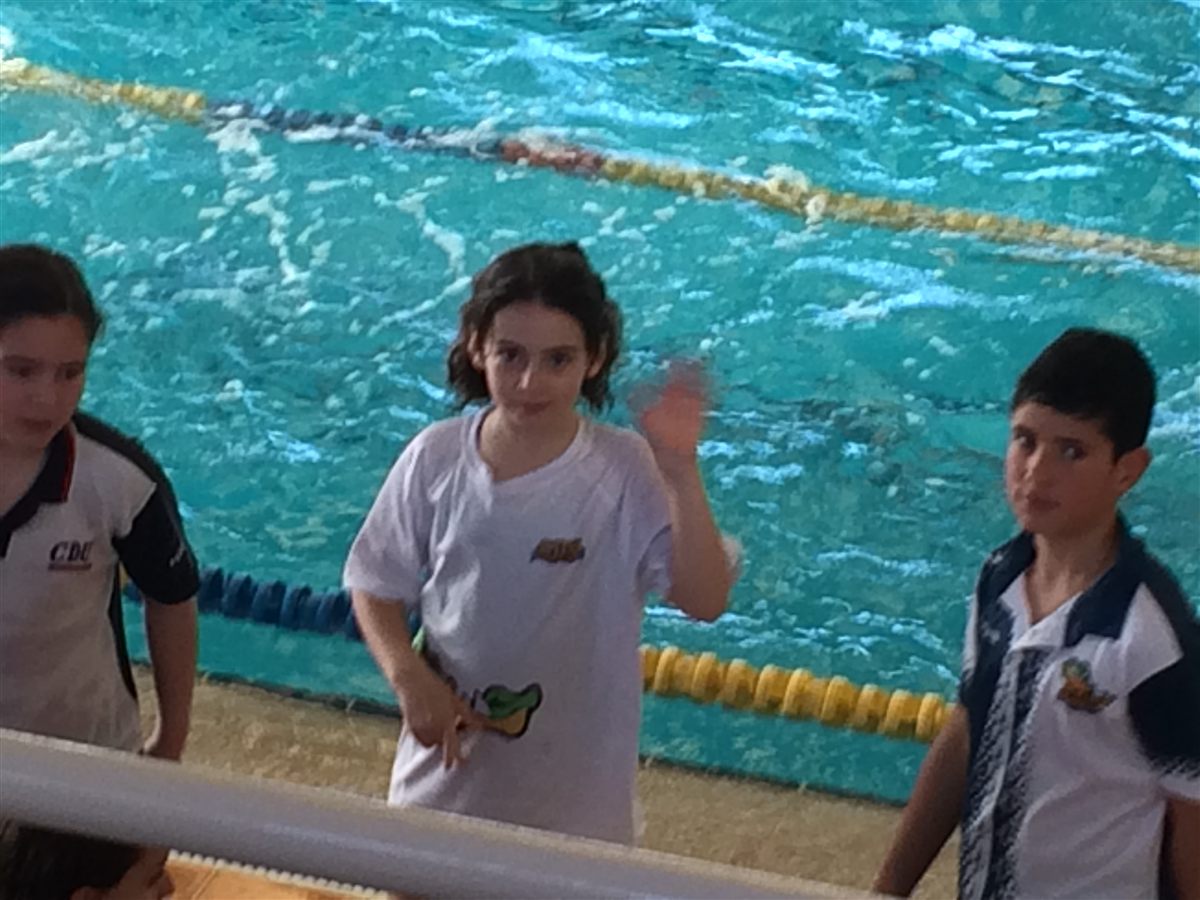 Zoë as a child in a green cap beside a pool during a competition