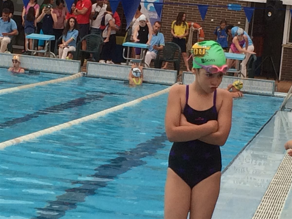 Zoë as a child in a club T-shirt waving beside the pool