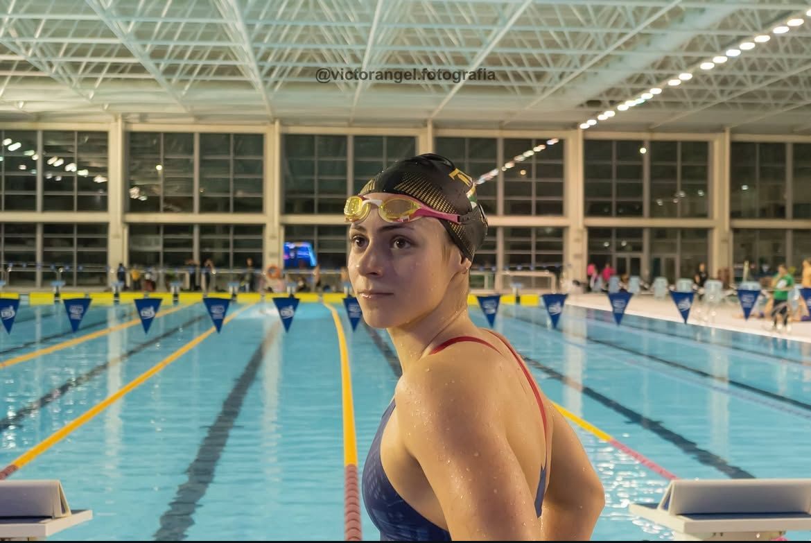 Zoë looking back over her shoulder beside a long-course pool