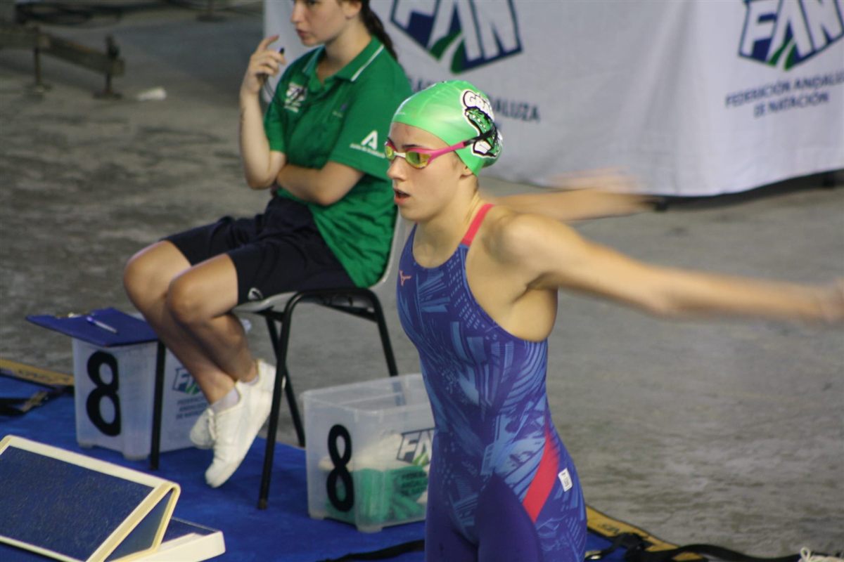 Swimmer with the green cap of the Andalusian team preparing on the starting block